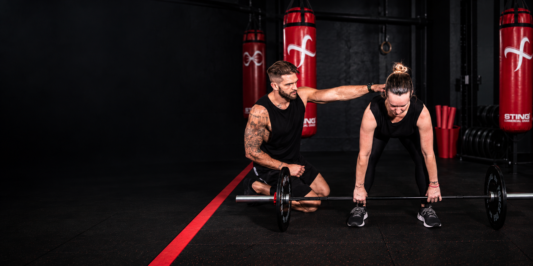 Jamie giving hands-on technique coaching during a landmine deadlift at Complete PT
